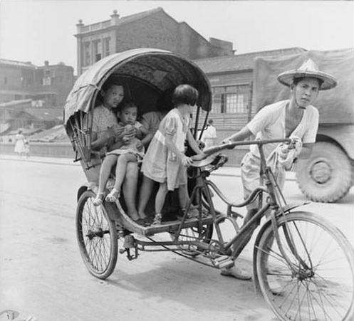 車伕拉著承載大人、小孩的三輪車